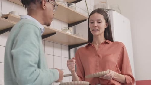 Couple Talking and Holding Plates in Kitchen