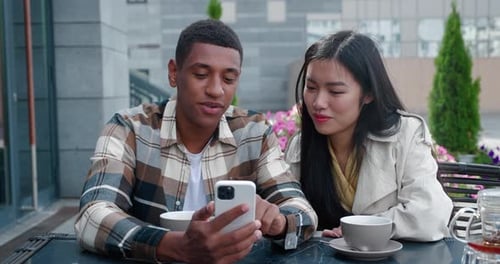 Two Beautiful Multiracial People Close Friends Talking Together Looking at the Mobile Phone