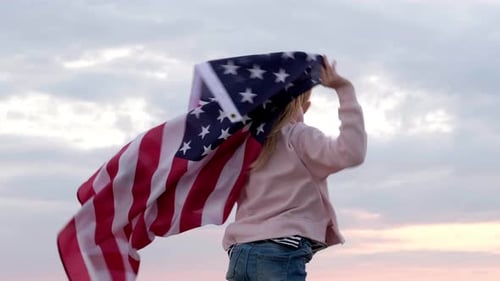 Girl Holds American Flag Against Sky Background