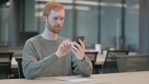 Attractive Young Man Using Smartphone in Office