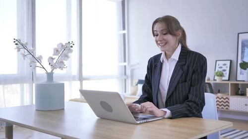 Young Woman Celebrates Success Using Laptop at Home