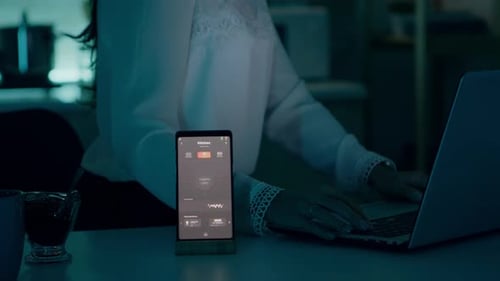 Woman Uses Smart Home App While Working on Laptop
