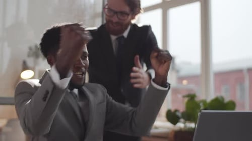 Two Joyous Multiethnic Businessmen Celebrating Achievement in Office