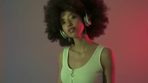 Young beautiful multiethnic woman indoor studio listening music using headphones on colorful backgro