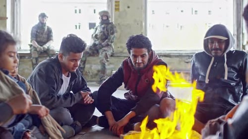 Refugiados calentándose por el fuego en un edificio abandonado