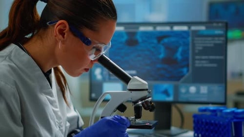 Woman Using Microscope for Scientific Research in Lab
