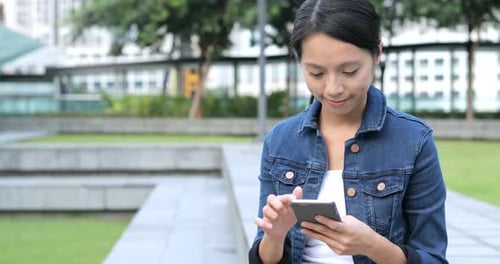 Young Woman Using Phone in City Park