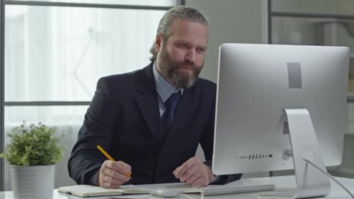 Bearded Man Working at Computer During Video Conference