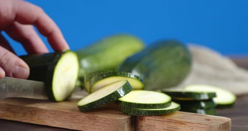 Slicing Fresh Green Zucchini on Cutting Board