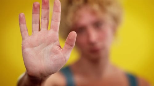 Nahaufnahme Männliche Hand mit verschwommenem kaukasischem LGBT-Mann auf gelbem Hintergrund