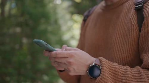 Smiling Man with Glasses with a Beard Walks Through the Woods with a Backpack and Prints a Message