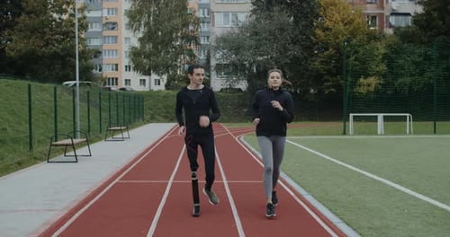 Man and Woman Jogging on an Urban Running Track