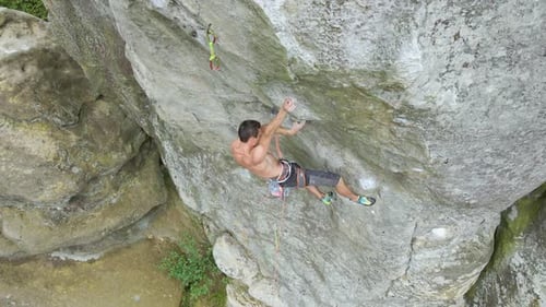 Young Man Climbing Steep Wall of Rocky Mountain