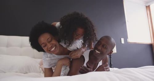 Happy Family Playing Together on Bed Indoors