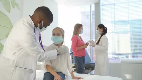 Male Doctor Examines Child Patient in Hospital Room
