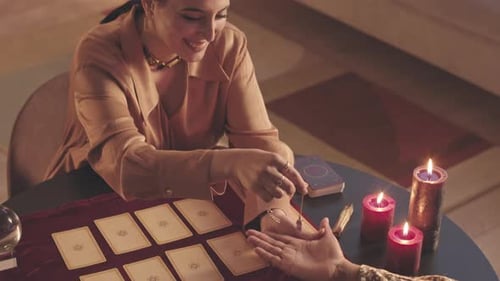 Fortune Teller with Pendulum and Tarot Cards Reading Palm of Woman