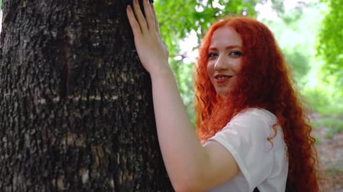 Woman with Touching Large Tree in Forest