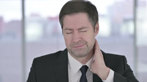 Man Rubbing Stiff Neck in Office Environment