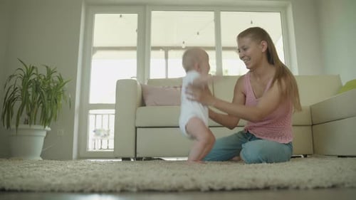 Woman Teaches Her Little Child To Walk At Home In The Room