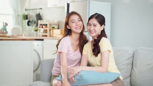 Two Young Women Smiling on Couch at Home