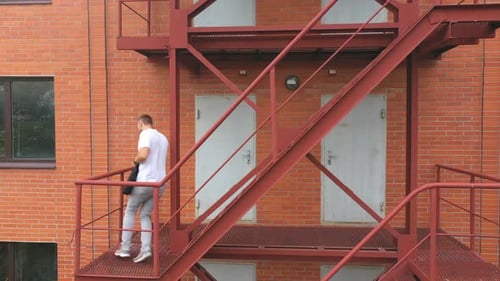 Man Walking Down Exterior Staircase Talking on Phone