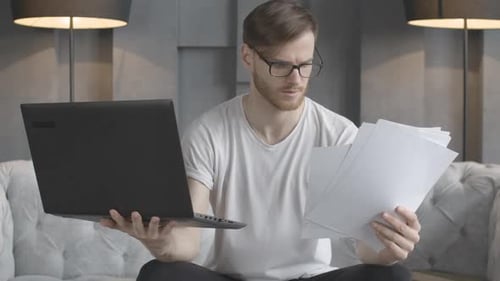 Nervous Young Caucasian Man Throwing Up Documents in Slow Motion As Looking at Laptop Screen