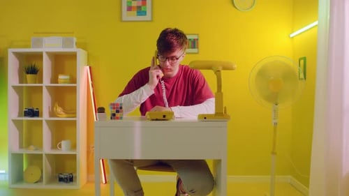 Young Adult Talking on Retro Yellow Landline Phone