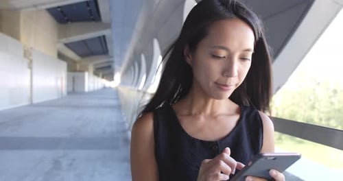 Woman Using Phone in a Modern Walkway