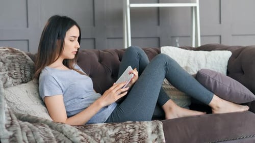 Woman Relaxes Reading Book on Cozy Couch