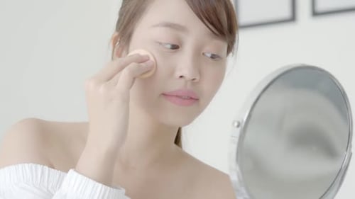 Young Woman Applies Makeup in Bright Setting