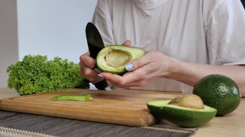 Woman Peels Fresh Avocado With Knife in Home
