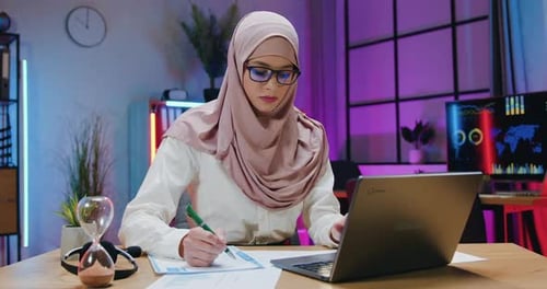 Woman Working at Desk with Laptop and Notes
