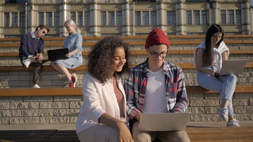 Students doing projects on laptops outside the university