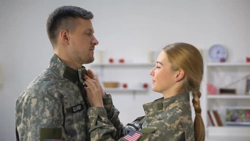 Woman Helping Soldier With His Camouflage Uniform