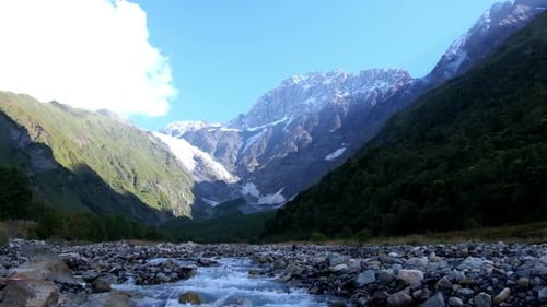 Gebirgsbach mit verschneitem Berggipfel