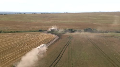 Aerial View of Cargo Truck Driving on Dirt Road Between Agricultural Wheat Fields Making Lot of Dust