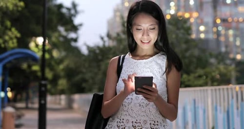 Woman using smart phone in city at night