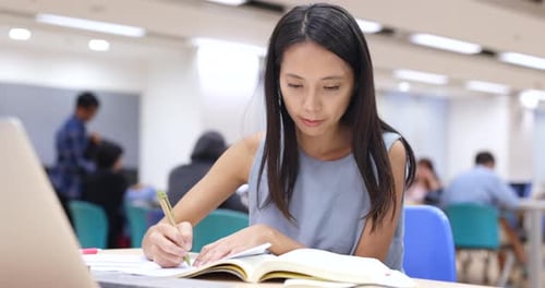 Frau arbeitet an Hausaufgaben in der Bibliothek