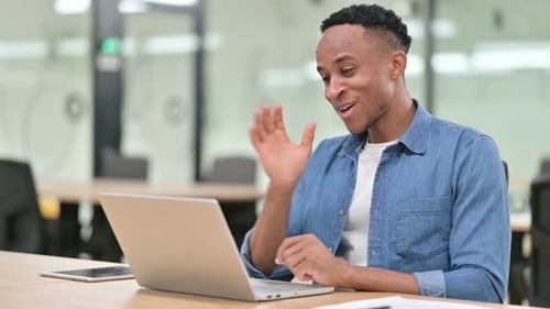 Casual African Man Doing Video Chat on Laptop in Office