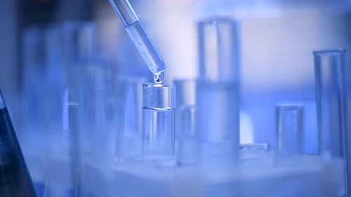 Pipette Dripping into Glass Test Tube in Lab