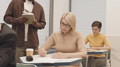 Mujer madura rubia haciendo examen de matemáticas en clase