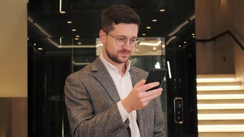 Young Adult Using Phone in Modern Elevator
