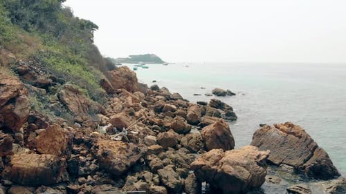 Camera Moves Along Beach Rocks Scattered at Hill Foot By Sea