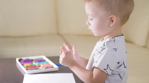 Little Child Playing with Colorful Modeling Clay Indoors