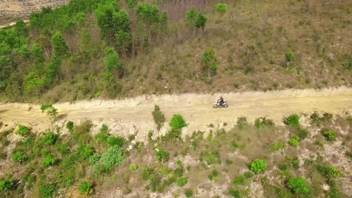Aerial Tracking Shot of Man Riding Bike on Dirt Road Downhill in the Mountain