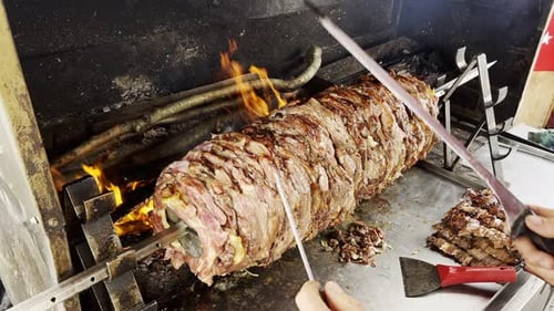 Delicious Meat Rotating on a Spit, Being Sliced