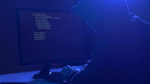 Hooded Hacker Coding in Dark Room