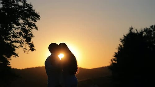 Romantic Couple Silhouetted Kissing at Sunset