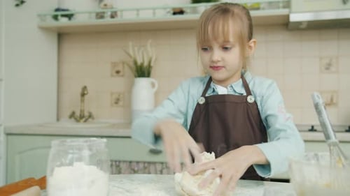 Cute Child Blond Girl in Apron Cooking in Kitchen Mixing Dough Adding Flour Making Pastry