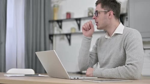 Man Coughing While Using Laptop At Home